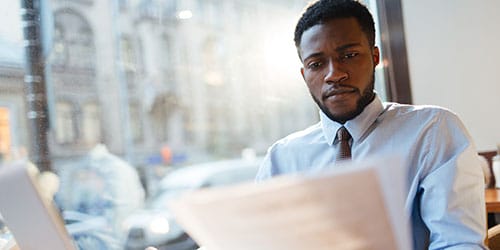 Serious employer reading resumes of candidates for vacancy