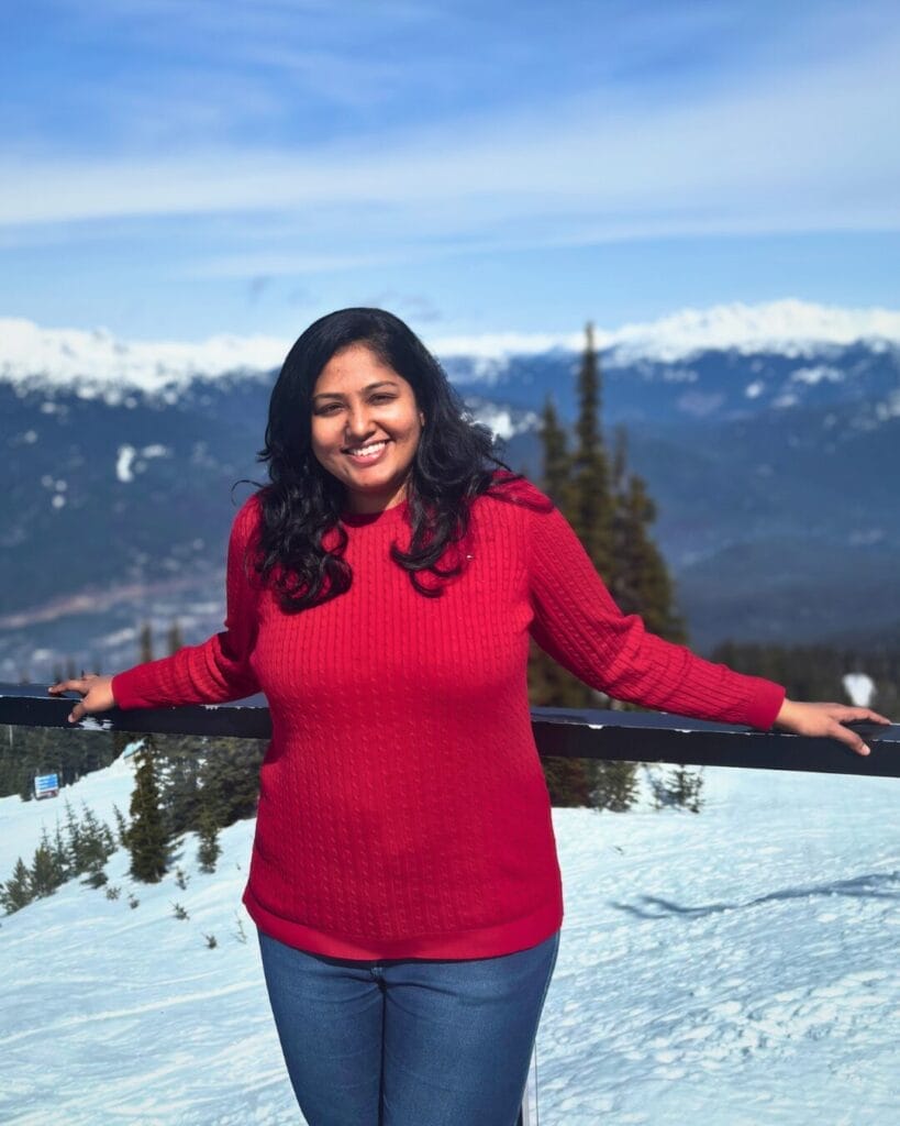 Jennifer D'souza standing on a pier with mountains in the background